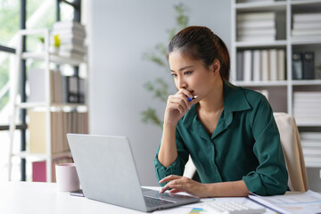 Focused businesswoman working with laptop and thinking about project in modern office