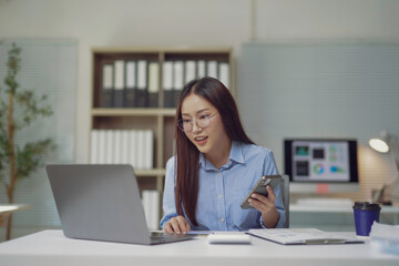 Asian businesswoman working with laptop and smartphone in modern office