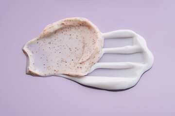 A smear of white cream and a scrub on a purple background.