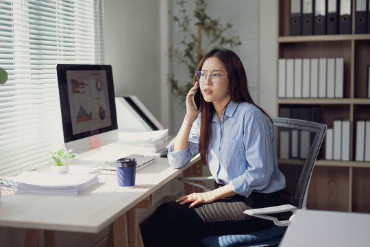 Businesswoman talking on phone and looking concerned at computer data charts in office