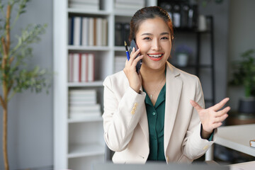 Asian businesswoman talking on phone and gesturing in office