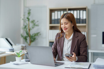 Asian businesswoman using laptop and smartphone working in office