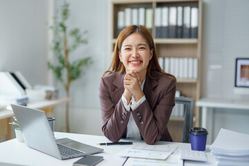 Smiling businesswoman sitting at desk with laptop and documents, working in modern office