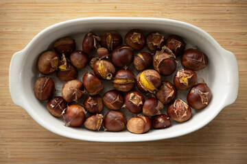Roasted chestnuts in a white bowl on a wooden table