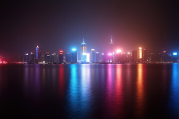 Fototapeta premium City skyline illuminated at night with vibrant lights reflecting on water
