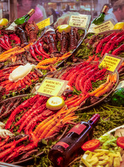 Portrait format picture of a Spanish fish restaurant display containing fresh fish, shellfish and assorted seafood. Vibrant reds, oranges and yellows