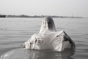 An Indian man taking a holy dip in the river ganges during early morning. 