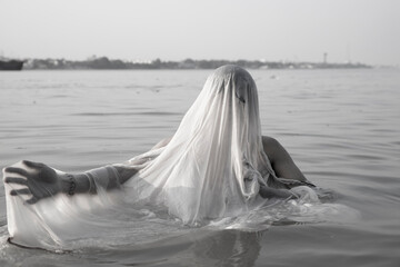 An Indian man taking a holy dip in the river ganges during early morning.
