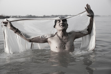 An Indian man taking a holy dip in the river ganges during early morning.