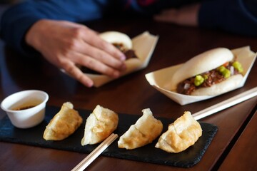 street food concept. faceless image, close up of a teenage boy eating a bao and gyozas