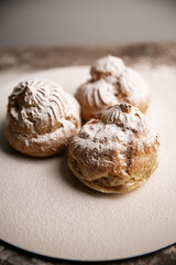 Decorating profiteroles with powdered sugar. Eclair with icing sugar