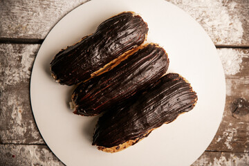 Chocolate eclair with a custard cream filling on a white plate