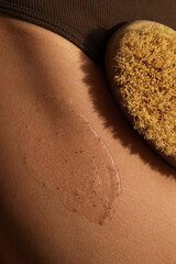 Close-up of woman's body, legs with body scrub. Scrub brush. Body wash and scrubbing - skin care...