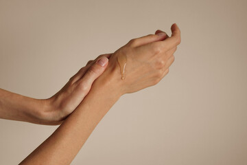 Close-up of woman's hands washing with minimal soap against a soft pastel beige background. Female....