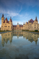 Majestic Moszna Castle on a warm summer morning, surrounded by lush greenery and glowing in soft golden sunlight, reflecting a fairytale-like ambiance perfect for travel and architecture themes.