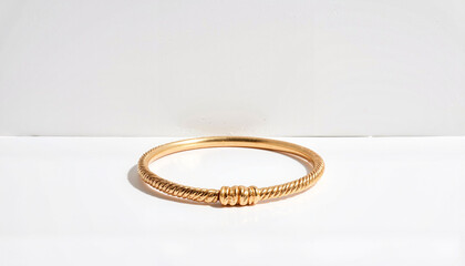 Elegant gold bangle showcasing twisted rope design on white surface, luxury