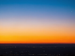 Fototapeta premium Colorful sunset over a city skyline with a clear horizon and soft evening glow at twilight