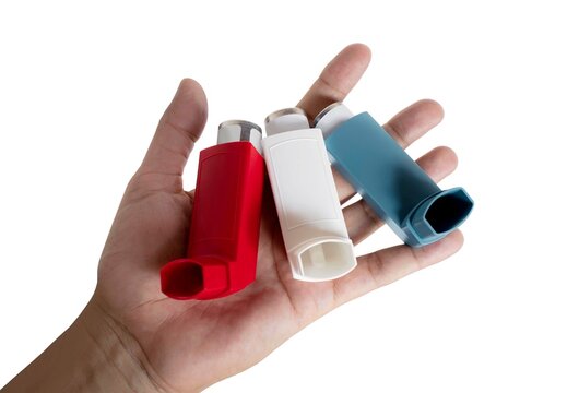 Three asthma inhalers in different colors on open hand, isolated on white background