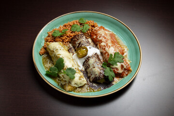Delicious enchiladas served with rice, cheese, cilantro, and different salsas on a turquoise plate
