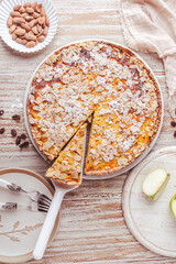 Homemade apple pie with roasted almonds on white wooden background
