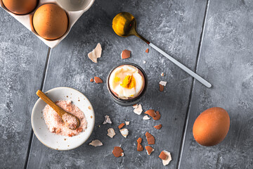 Boiled brown egg where the top is cut off in gray egg cup on gray background