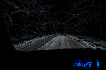 Car cockpit view of night car driving in winter forest