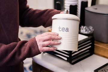 Person hands holding a tin jar of tea. Woman opening a box container of tea close up