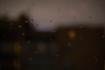 Evening landscape. Water Drops on Rain window glass .Transparent Glass in rainy day. View of city from the window.
