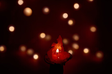 One red candle flame at night against defocused bokeh lights on dark background, Romantic St Valentine's decor 