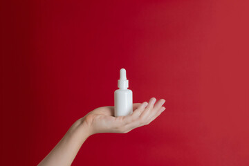 Serum glass unbranded bottle (essential oil) with pipette on red background. Natural moisturizing, nourishing cosmetics for skin, beauty and spa