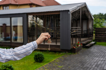 Hand holding keys to new house. Moving relocation concept, real estate concept. Buying or renting
