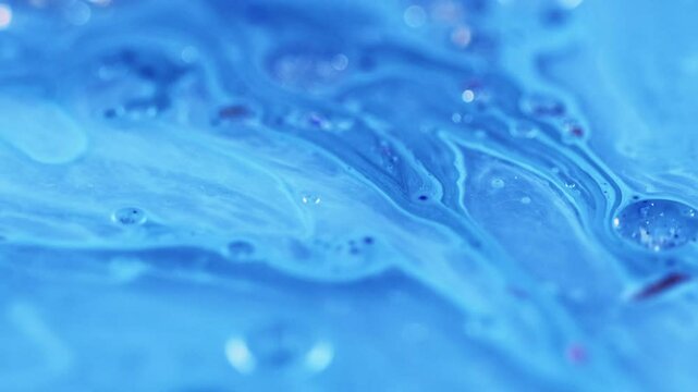 Emulsion mix. Shiny fluid drop. Defocused blue color sparkling glitter particles gloss bubbles water dye liquid ink blend motion abstract art background.