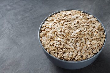 Oat Flakes in Bowl on Dark Gray Background, Copy Space