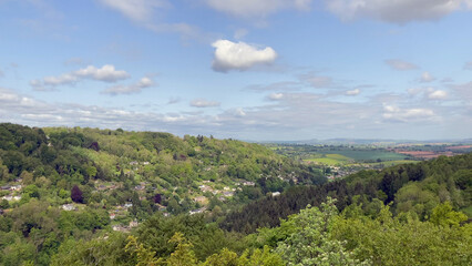 Beautiful natural scenery showcasing a peaceful countryside with green hills, scattered trees, and a Symonds Yat village nestled amidst nature under a bright sky - Herefordshire, UK