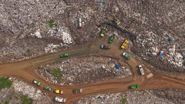 Aerial top view of A Huge Waste, garbage, dump, rubbish landfill. A landfill compactor, group of workers sort out the garbage in the landfill. Trash trucks dump waste polluting products.
