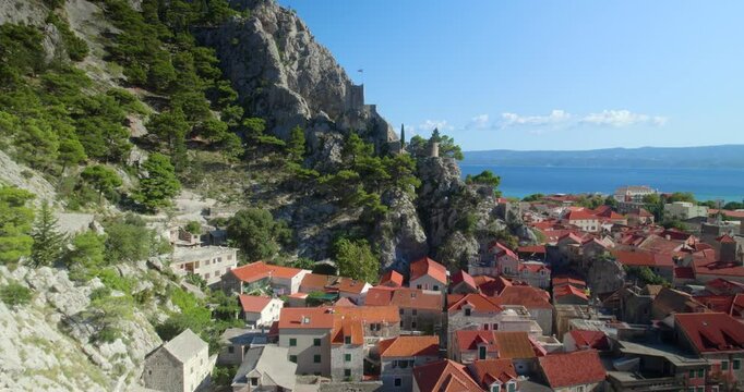 Aerial drone view of the coastal town of Omis in the south of Croatia. Town&rsquo;s stunning historic castle perched on a hilltop overlooking the Adriatic Sea.