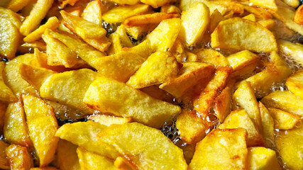 Tasty crispy fried wedges of potato with fresh rosemary served in an old metal skillet in a close up wide