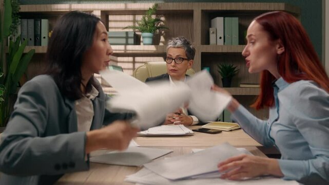 Angry nervous diversity women disagreement conflict argue shouting throwing papers documents paperwork office business leader employees chaotic co-workers businesswomen indoors partnership colleagues