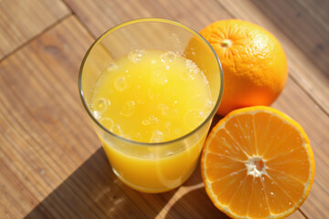 Freshly squeezed orange juice with sliced orange in sunlight