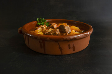 Rustic beef stew with potatoes served in a clay bowl. Hearty and traditional homemade dish, rich in flavor, perfect for comfort food or culinary photography concepts.