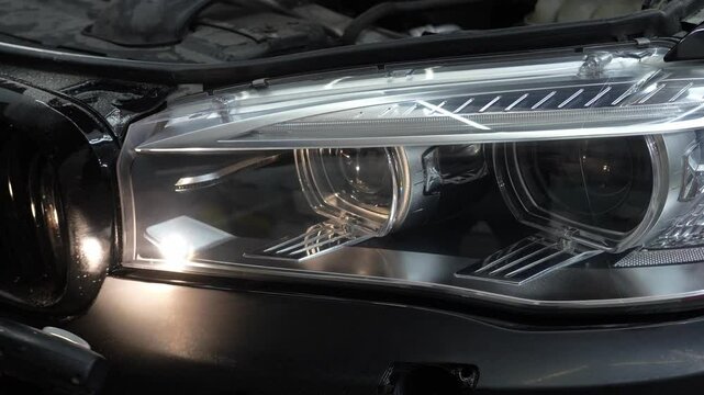 Headlight after detailing procedures of polishing and waxing a vehicle 4k video. Cleaner worker is inspecting the car headlight after washing automobile with microfiber and detergent.