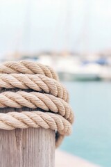 Fototapeta premium Twisted rope wrapped around wooden post, with serene water and b