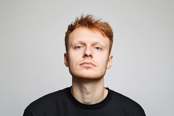 Fototapeta premium Confident young man with striking red hair poses against neutral