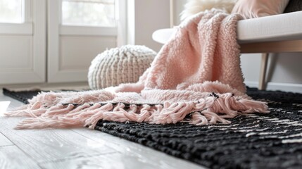A light pink, fluffy blanket with fringed edges lies on the floor of a modern interior