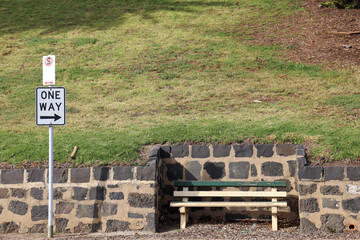 empty park bench in park with one way sign