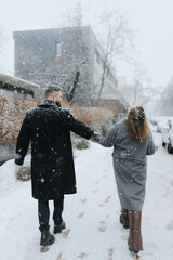 Couple walking hand in hand through a snow-covered street on a chilly winter day