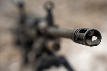 A military rifle is positioned on a bipod atop a dirt surface. The weapon appears ready for a training session. Surrounding debris indicates a dynamic training environment.