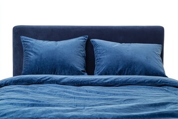 A neatly made bed with two blue pillows on top of it. The pillows are fluffy and the bedspread is a deep blue color. The bed is positioned against a white background, creating a clean