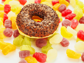 Chocolate round donut with sprinkles on colorful sweet jelly candy. High level of sugar....