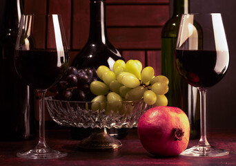 A stylized antique still life with glasses of wine, fruit and three wine bottles